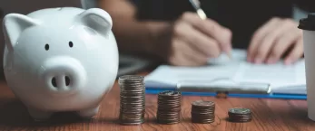 Piggy bank in front of person writing